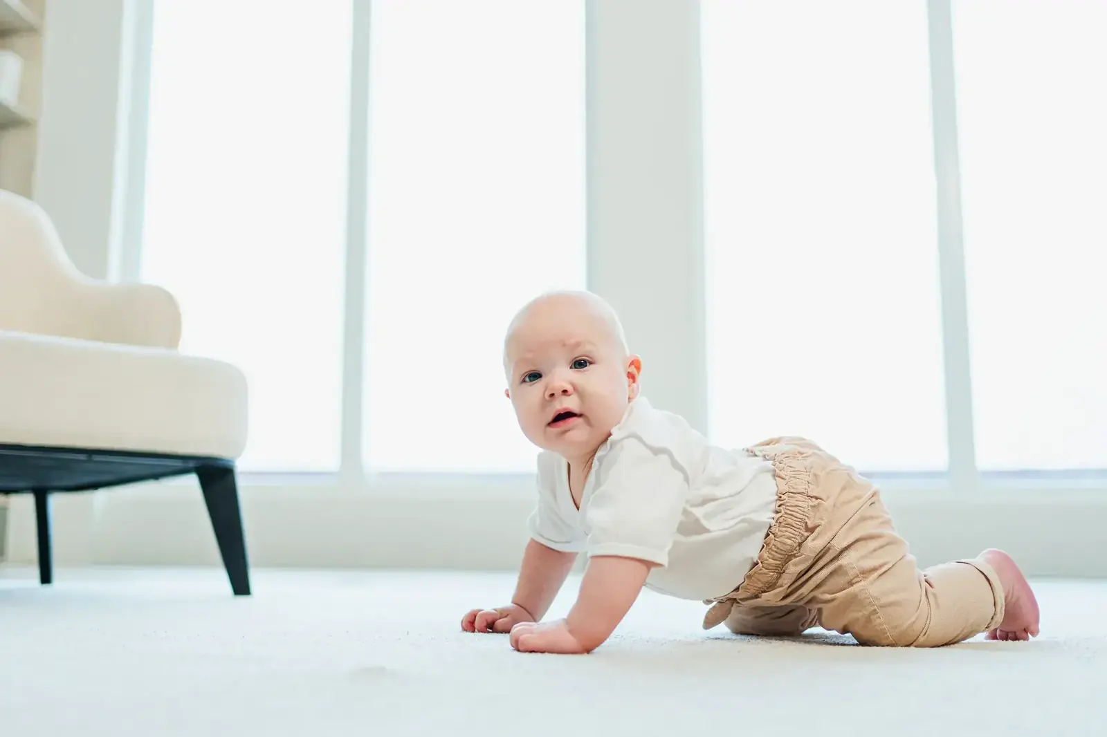 Baby crawling across a bright, clean living room floor