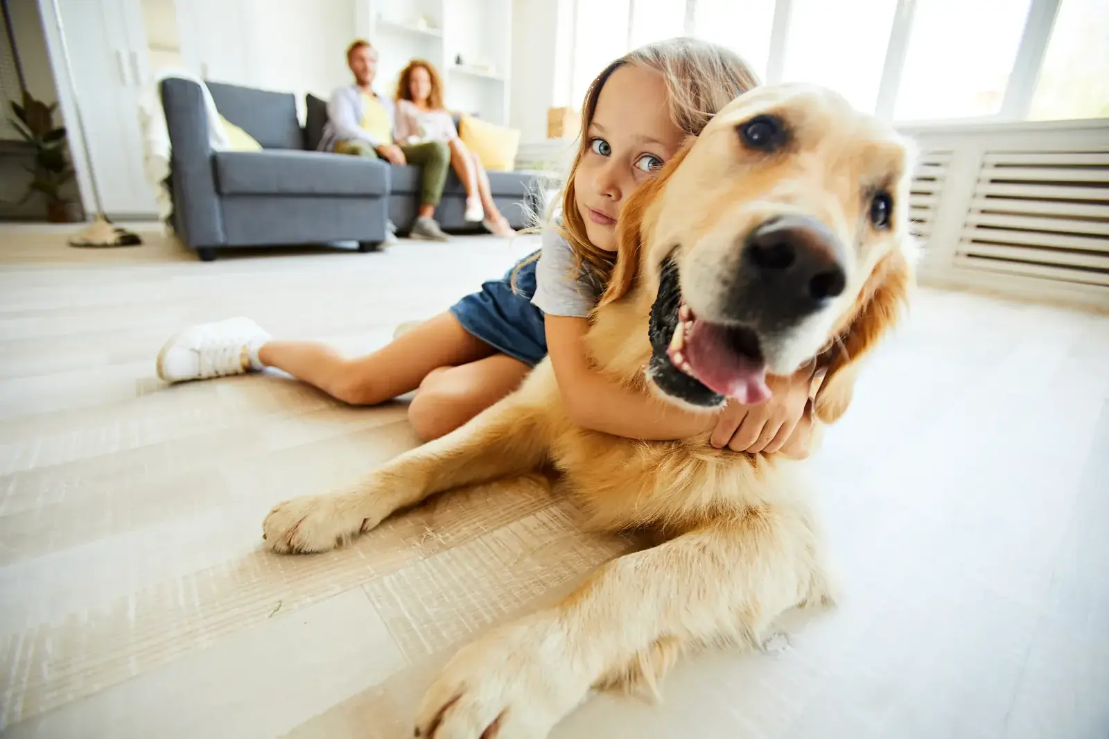 Girl hugging her golden retriever on a clean living room floor