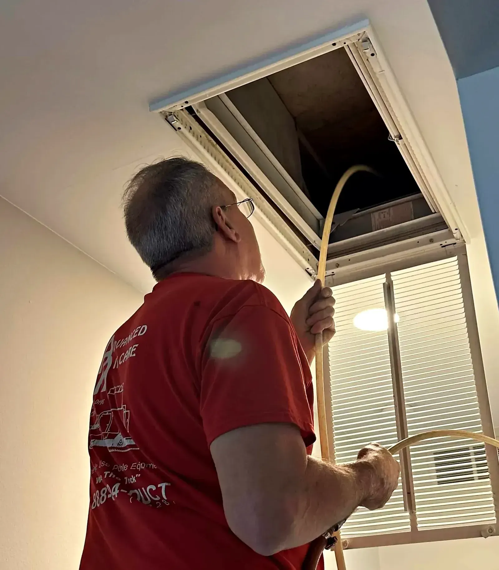 Technician cleaning a ceiling supply register